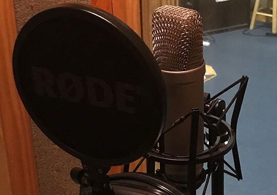 Image of a RODE NT1-A microphone with a pop filter and headphone, prepped for recording.